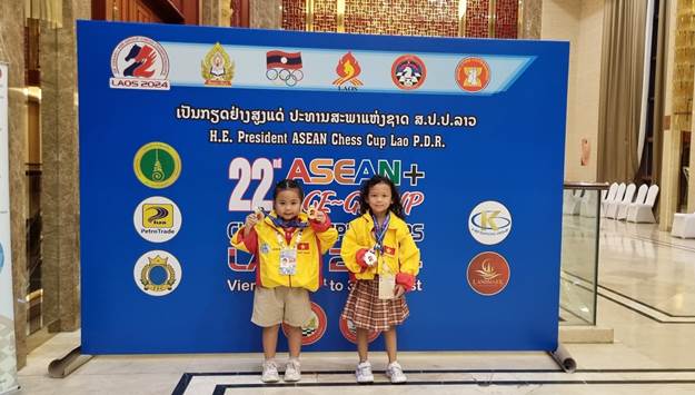 A couple of young girls standing in front of a blue sign
Description automatically generated